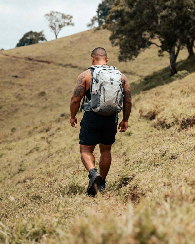 Beginner hiker walking uphill with a light daypack to build strength and balance for hiking.